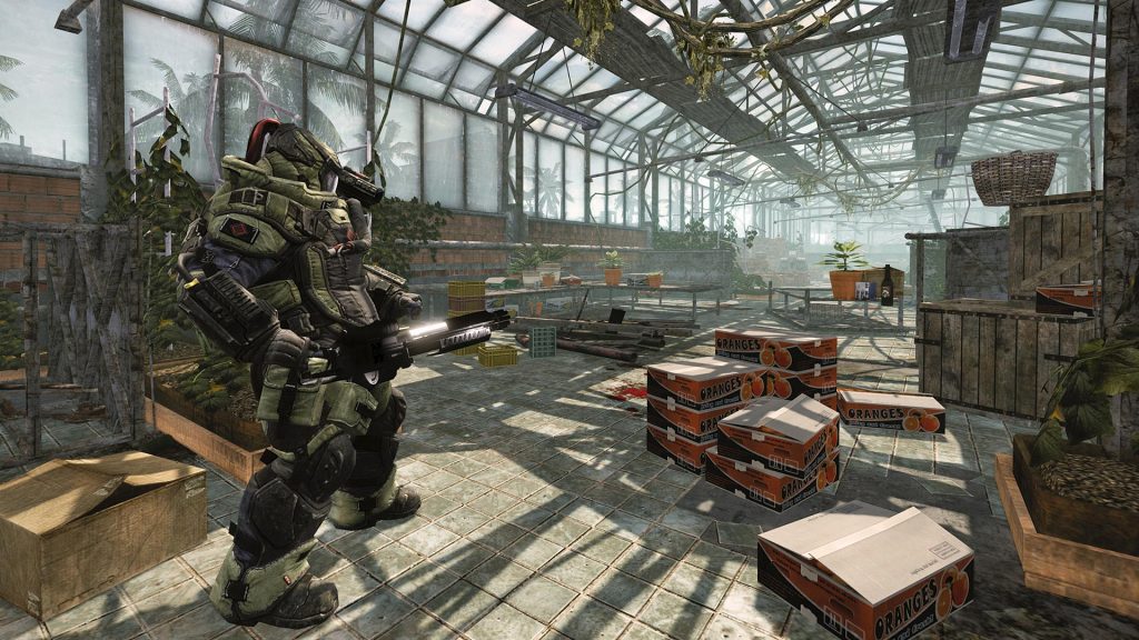 Armored soldier character aiming a rifle inside a glass-roofed greenhouse filled with crates labeled Oranges, in Warface