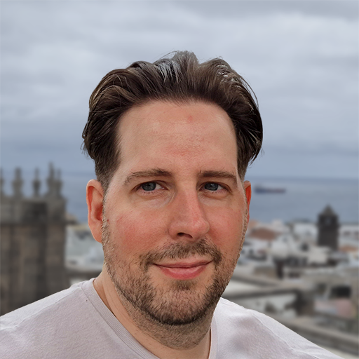 Portrait photo of Tobias Bertrand outdoors with a coastal town and church spires in the background